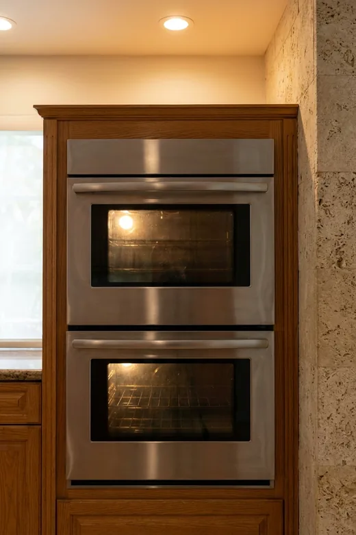 GE Monogram built-in wall ovens set into a stone-clad cabinet
